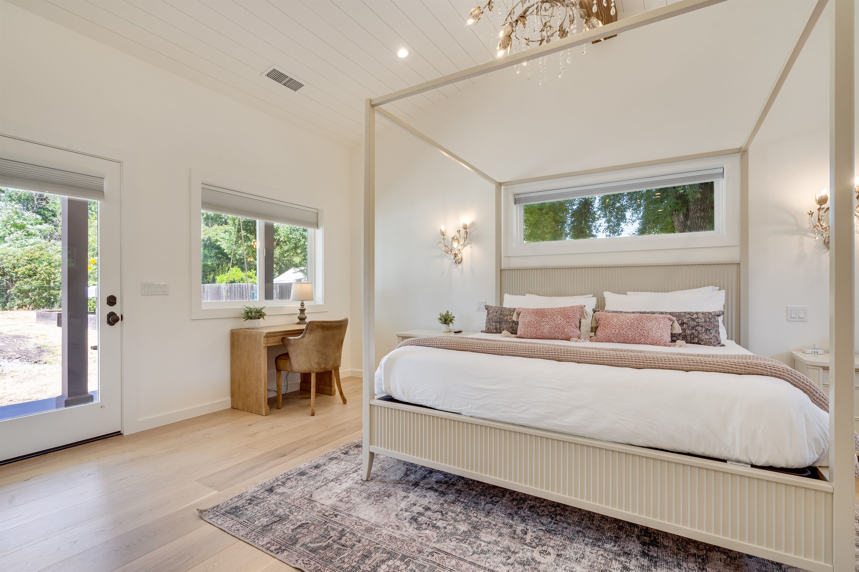 Een slaapkamer met een hemelbed, een bureau en een stoel.
