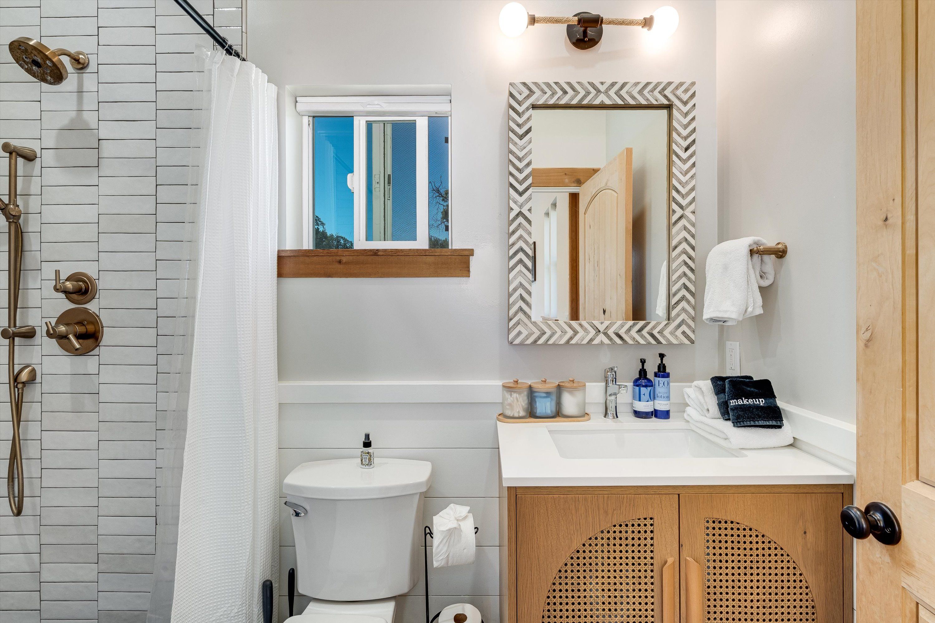 A bathroom with a shower, toilet, sink, and vanity.