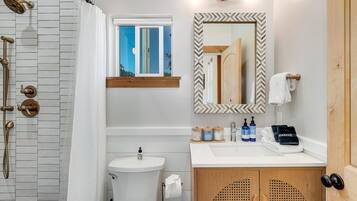 A bathroom with a shower, toilet, sink, and vanity.
