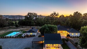 A modern house with a swimming pool, covered patio, and a well-maintained lawn.