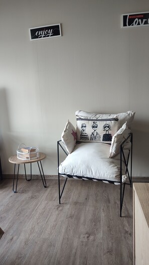 A minimalist room with a sofa, pillows, a small round table with a basket, and two wall signs.