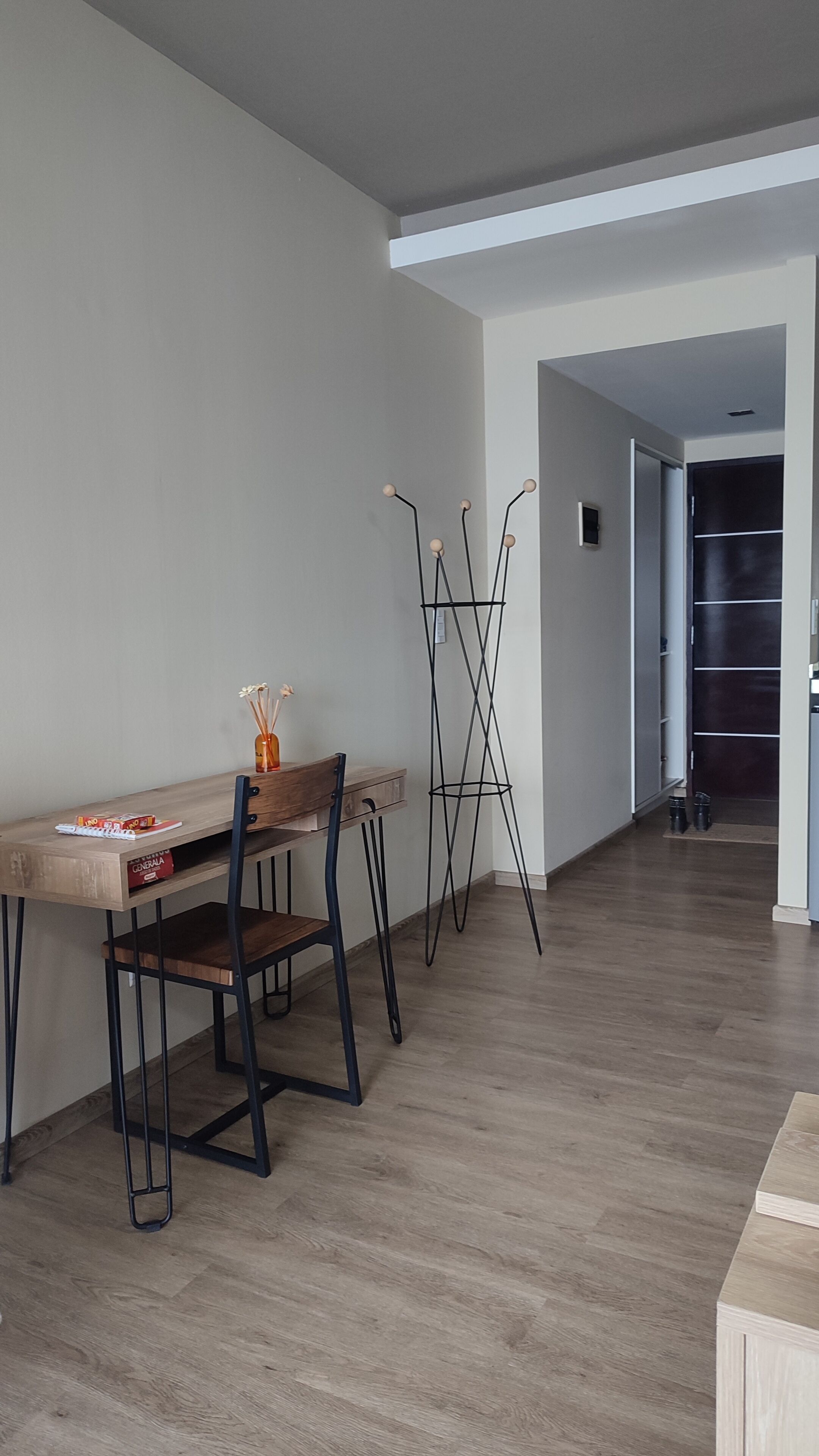 Un espace repas moderne avec une table et des chaises en bois, un grand lampadaire et, au fond, une armoire en bois sombre.