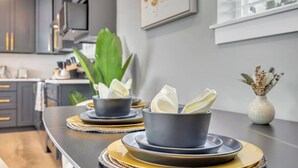 A modern kitchen with grey cabinets, a large green plant, and two bowls with napkins on a table.