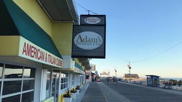 Un paseo marítimo con restaurantes, entre ellos 'Adam's Restaurant & Bar' y 'Red Parrot Lounge'.