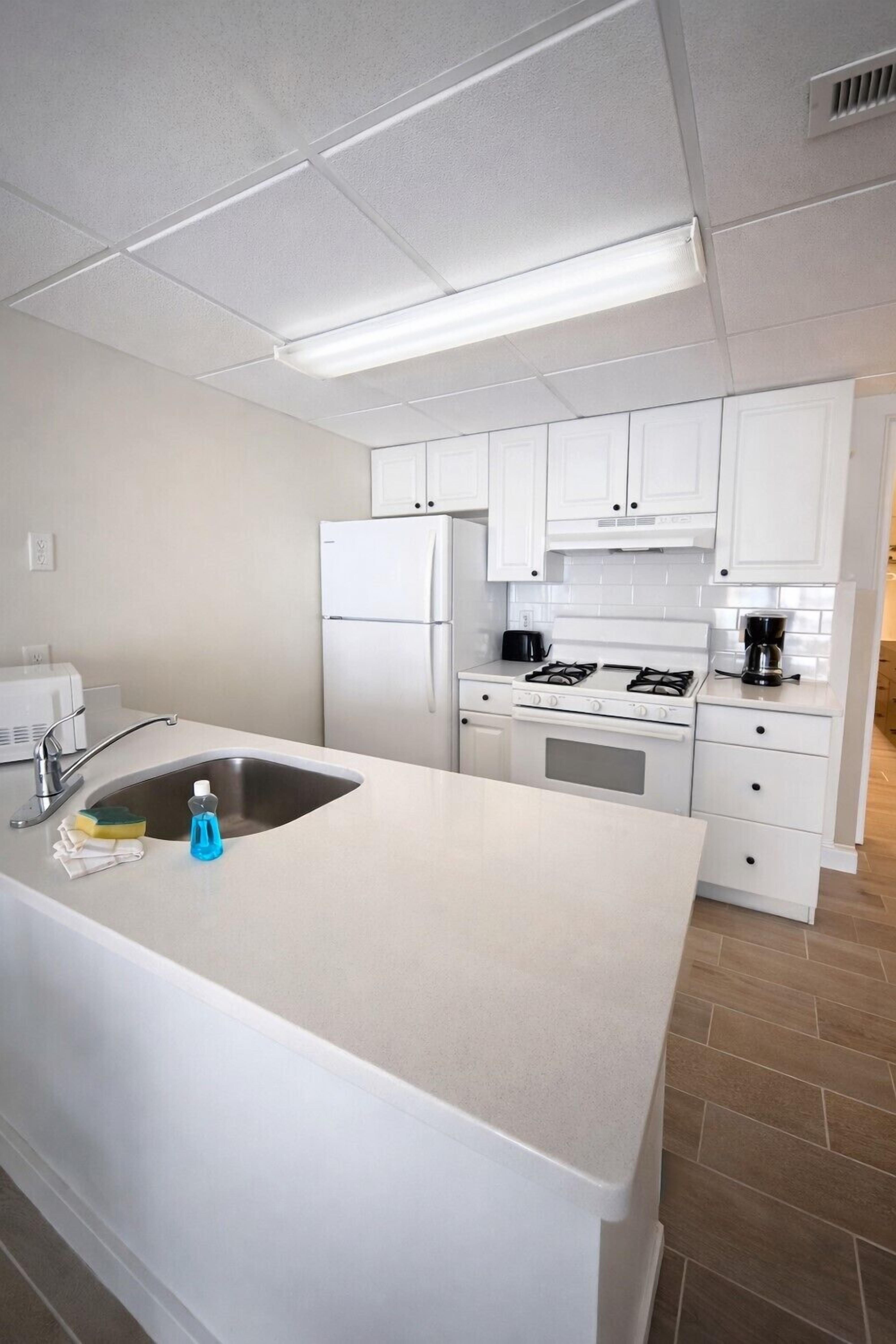 A modern kitchen with white cabinets, a stainless steel sink, and a gas stove.