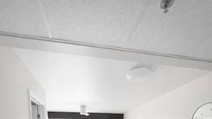 Habitación moderna y luminosa con zona de comedor que incluye una mesa redonda y sillas, un sofá, y un amplio ventanal con cortinas.