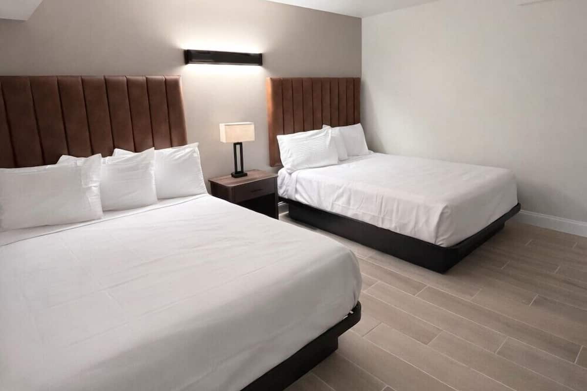 A hotel room with two beds, a nightstand with a lamp, and a sloped ceiling.