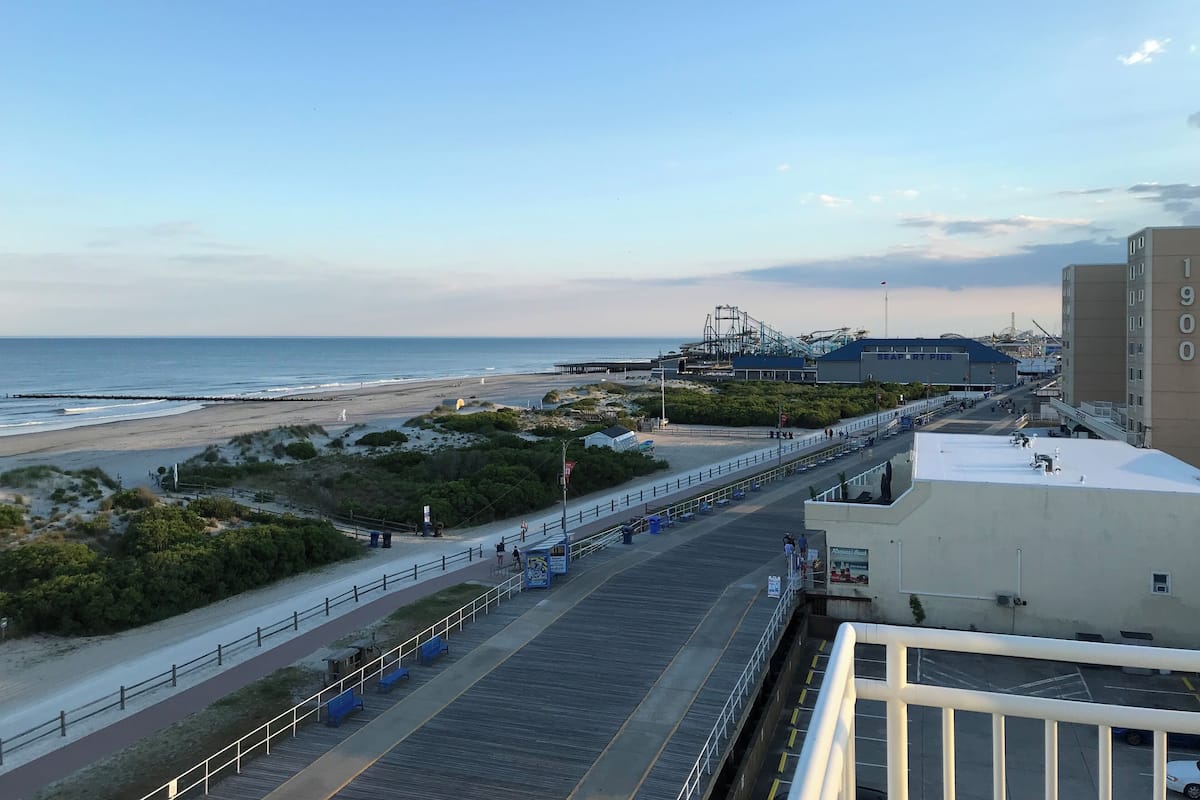 A coastal view with a beach, a pier, and industrial buildings.