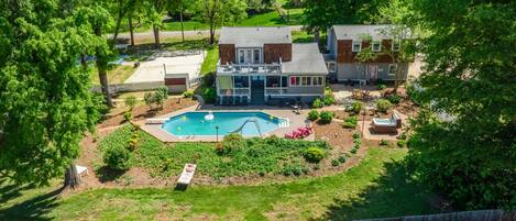 A residential property with a swimming pool, a covered patio, and a fenced yard.