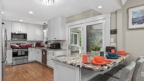 A modern kitchen with white cabinetry, stainless steel appliances, and a granite countertop.