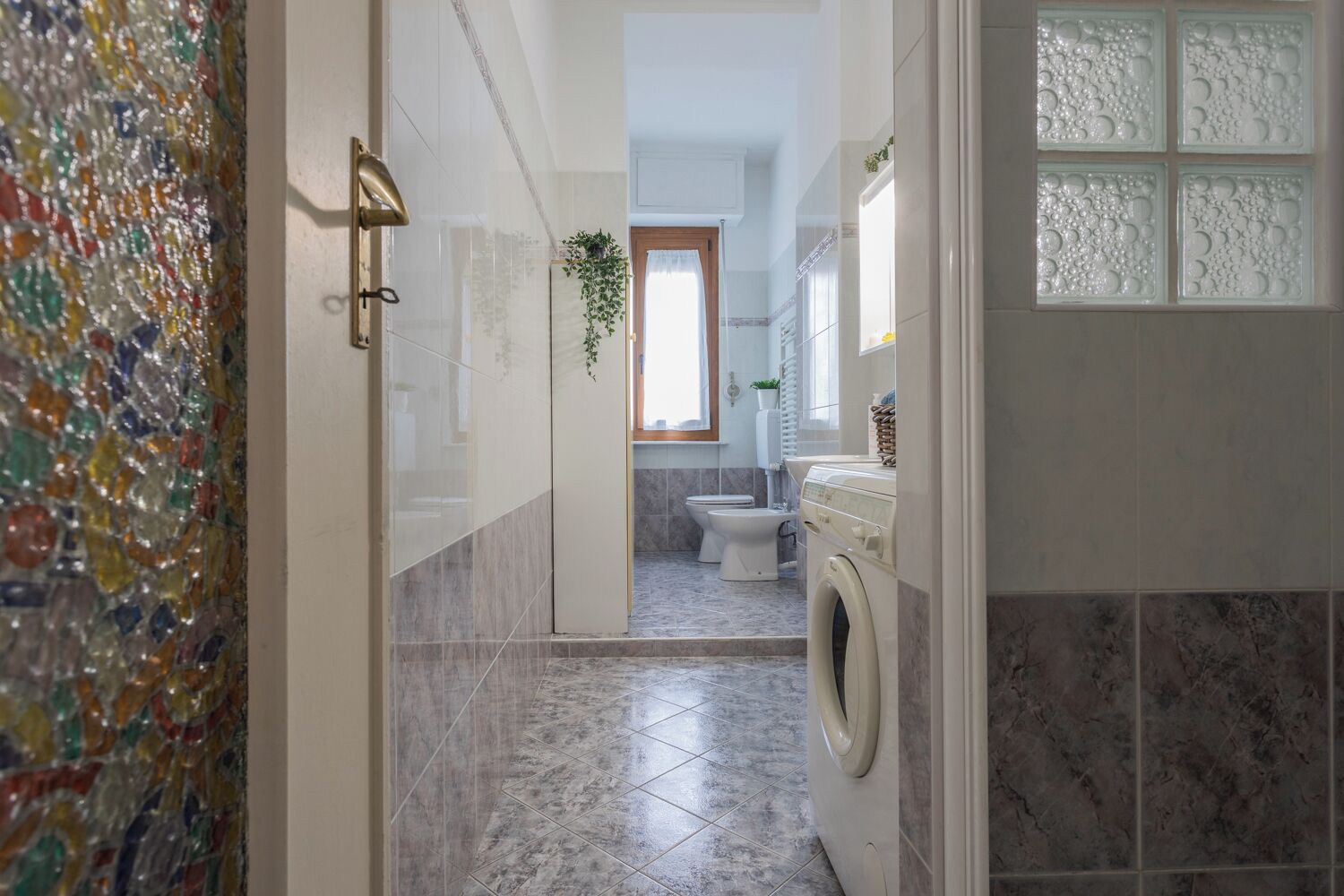A bathroom with a washing machine, a toilet, and a shower area.