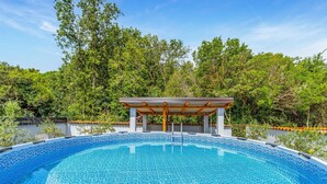 Una piscina con estructura de pérgola, rodeada de abundante vegetación.