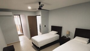 A hotel room with two beds, a ceiling fan, and a small bedside table with a lamp. - Torre Metropoli (Cancun)
