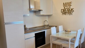 A modern kitchen with white cabinetry, a built-in oven, and a dining area with a white table and chairs. - Vitti's home verona 2 - Cittadella  (Verona)