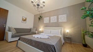 A bedroom with a bed, a sofa, a chandelier, and decorative wall art. - Vitti's home verona 2 - Cittadella  (Verona)