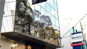 A modern hotel with a reflective glass facade, a prominent 'HOTEL' sign, and a 'We Vets' veterinary center sign. - Hotel Mooca São Paulo (São Paulo)