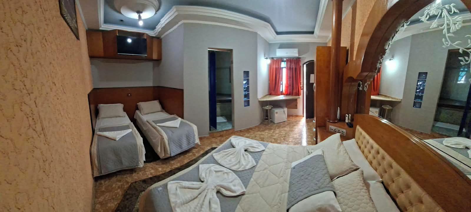 Quarto de hotel com duas camas, um espelho grande e um ventilador de teto.