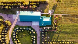 An aerial view of a large building with a green roof, surrounded by a circular garden with trees, a paved driveway, and a field. - Secluded & Spacious Log Cabin Lodge Located in Western Nebraska - Pet-friendly! (Lodgepole)