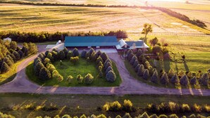 An aerial view of a large building with a green roof, surrounded by a well-maintained lawn and a variety of trees. - Secluded & Spacious Log Cabin Lodge Located in Western Nebraska - Pet-friendly! (Lodgepole)