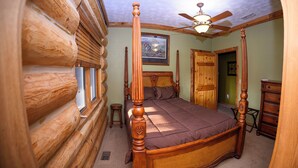 A log cabin bedroom with a four-poster bed, wooden walls, a ceiling fan, and a framed picture on the wall. - Secluded & Spacious Log Cabin Lodge Located in Western Nebraska - Pet-friendly! (Lodgepole)