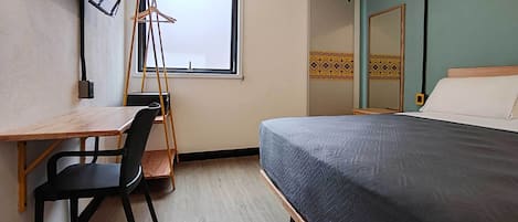 Une chambre à coucher avec un lit, un bureau et une chaise, une échelle et une fenêtre.