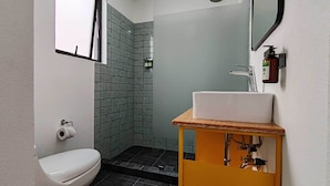 Ein Badezimmer mit Toilette, Waschbecken und Duschbereich mit gefliesten Wänden.