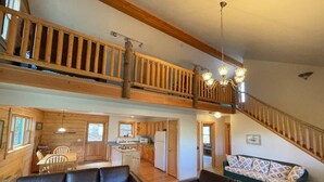 A spacious living area with a high ceiling, wooden staircase, and a kitchen in the background. - Mountain Meadow Cabin in Cotopaxi on 40 acres (Cotopaxi)