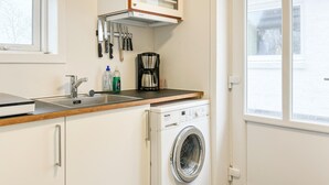 A compact kitchen with a sink, a coffee maker, and a washing machine.