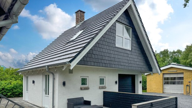 A modern house with a sloped roof, a small porch with a bench, and a garage.