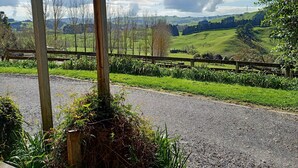 Un espacio al aire libre techado con un sendero de grava, cerca de madera y follaje.