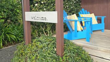 A wooden structure with a 'welcome' sign, blue chairs with yellow cushions, and a wooden deck.