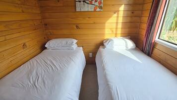 Een kamer met twee eenpersoonsbedden, houten wanden, een raam met gordijnen en een decoratie van uilen op de muur.