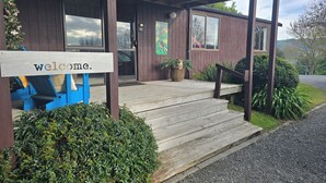 Un edificio de madera con un cartel de 'welcome', un porche cubierto y una escalera que lleva a la entrada.