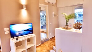 Una sala de estar con un televisor sobre un mueble bajo, una planta en maceta y un modelo de barco sobre una mesa.