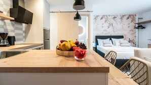 Une cuisine moderne avec un plan de travail en bois, un panier de fruits et une suspension lumineuse.