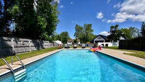 A rectangular swimming pool with a metal ladder on one side, surrounded by a wooden fence and a grassy lawn. - "Good Vibes" 4 Wonderful Seasons @ Portland Home! (Portland)