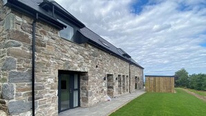 A stone building with a modern design, featuring a large window and a door. - Essich Park - 3BR - Hot Tub - Sleeps 6 (Essich)