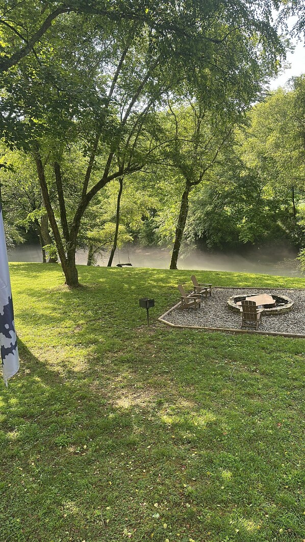 A park with a fire pit, benches, and a swing set. - The Riverhaus @nottelyriverhaus on IG. (Murphy)