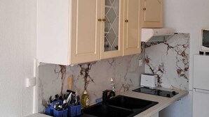 Una cocina con armarios color beige, un lavamanos doble, un tostador y un refrigerador.