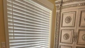 Ein Essbereich mit Tisch und Stühlen, einem Fenster mit Jalousien und einem dekorativen Schrank.