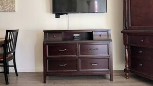 Un aparador de madera oscura con varios cajones y un televisor de pantalla plana montado encima.