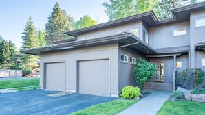 A two-story house with a garage, a covered porch, and a well-maintained lawn.