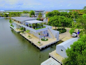 A waterfront property with multiple buildings connected by walkways, featuring outdoor seating areas and a dock.
