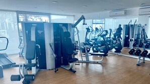 Uma academia com aparelhos de cardio, estações de musculação e halteres.