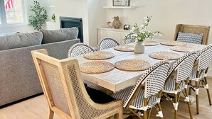 Un comedor con una mesa y sillas de madera, un lámpara colgante y un televisor montado en la pared.