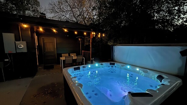 Un jacuzzi con luces LED, un área de patio con sillas y una pantalla de proyector.