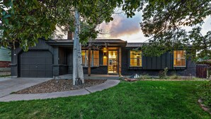 Una casa moderna de dos pisos con fachada oscura, césped cuidado y garaje.