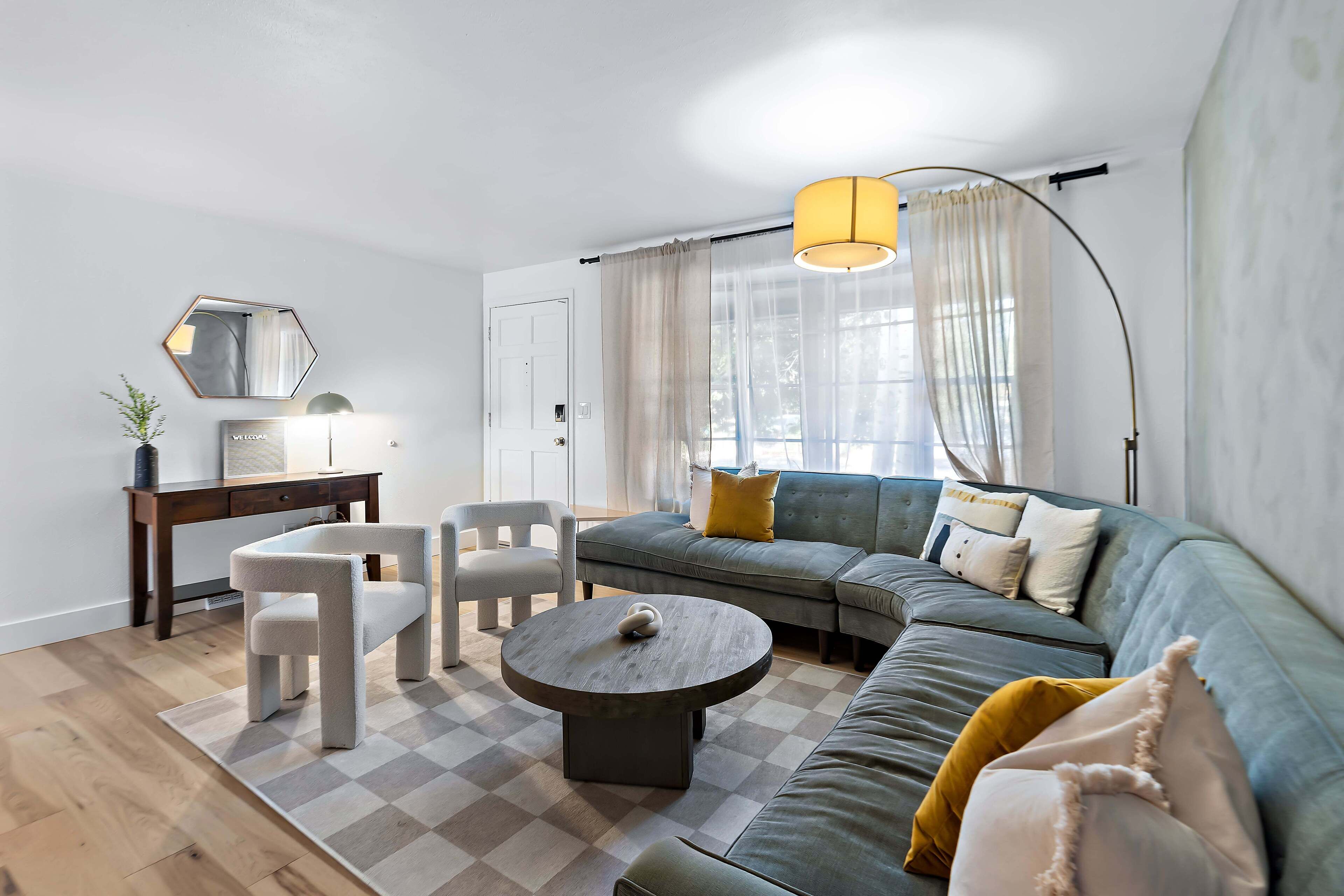 A modern living room with a sofa, chairs, a coffee table, and a desk.