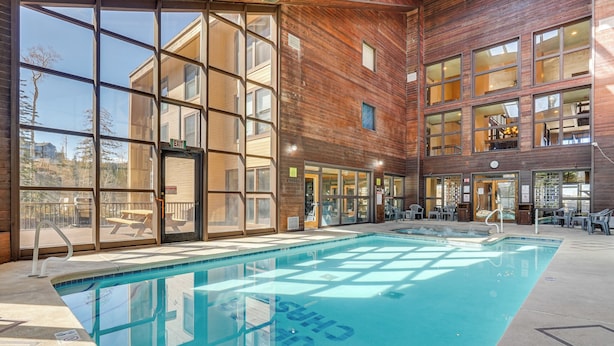 An indoor swimming pool with clear glass walls, a wooden exterior, and a view of the outside. - Hiking & Explore: Brian Head Condo w/ Indoor Pool! (Brian Head)