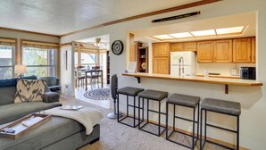 A modern kitchen with wooden cabinets, a bar area with stools, and a dining area with a round table and chairs. - Hiking & Explore: Brian Head Condo w/ Indoor Pool! (Brian Head)